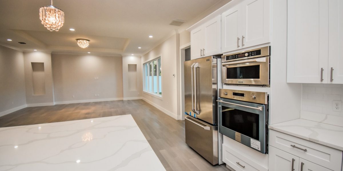 mage of a Stunning Open Concept Kitchen Featuring Stainless Steel Luxury Appliances, Hardwood Floors, Crown Mouldings, White Calacatta Cascade Countertops, and White Kitchen Cabinets - A Blend of Classic and Modern Design Elements